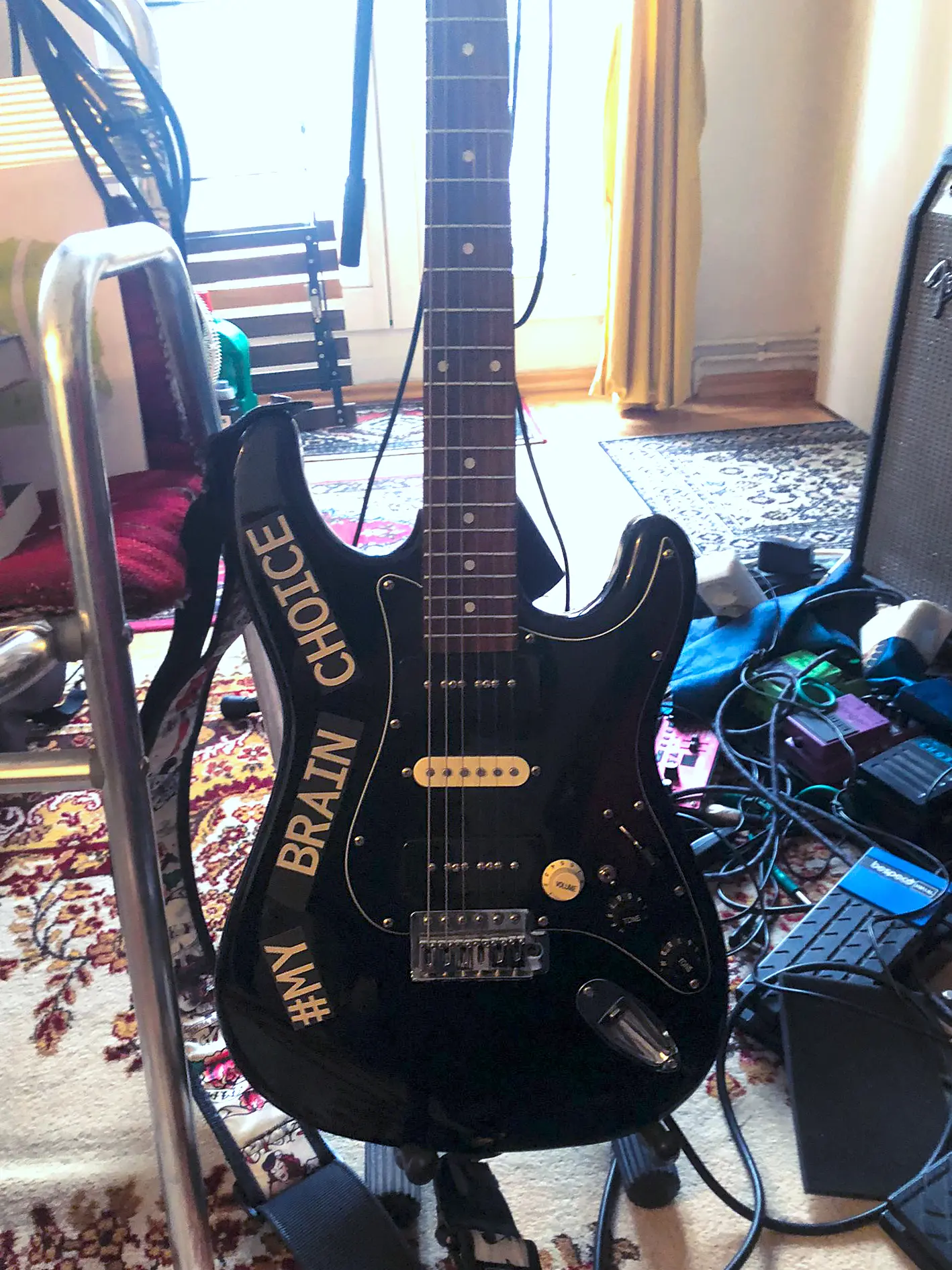 Die im Text beschriebe Gitarre des Autors. Eine schwarze E-Gitarre mit einem großen Schriftzug "My Brain My Choice".