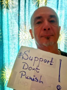 Selfie mit einem Schild mit der Handschrift "Support Dont Punish"