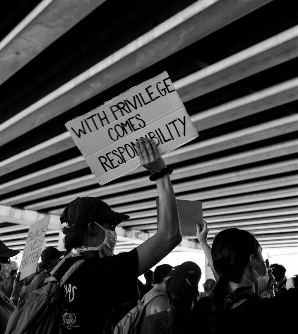 Ein Demonstrant hält ein Schild hoch, auf dem steht "With priviledge comes responsibility", zu deutsch: Privilegien bringen Verantwortung