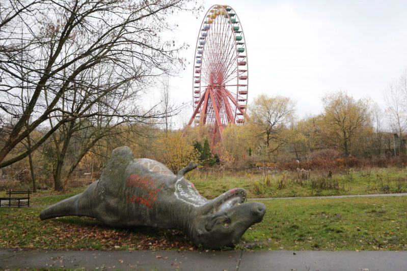 Symbolbild für das Versagen der Stadtentwicklungspolitik: Eine umgefallene Dino-Statue, eine trübe Stadtszene